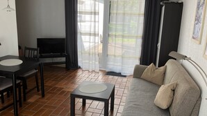 A living room with a sofa, a TV, a table, and a chair. - Apartment '' with Private Terrace, Shared Garden and Wi-Fi (Warstein)