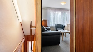 Una habitación con sofá, una mesita, una lámpara y una ventana con cortinas.