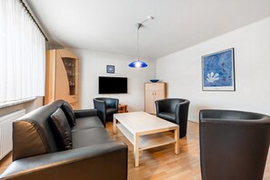 A modern living room with a sofa, chairs, a coffee table, a TV, and a cabinet.