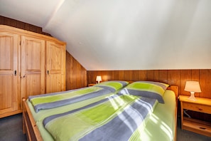 A bedroom with a bed, wooden wardrobe, and nightstands.