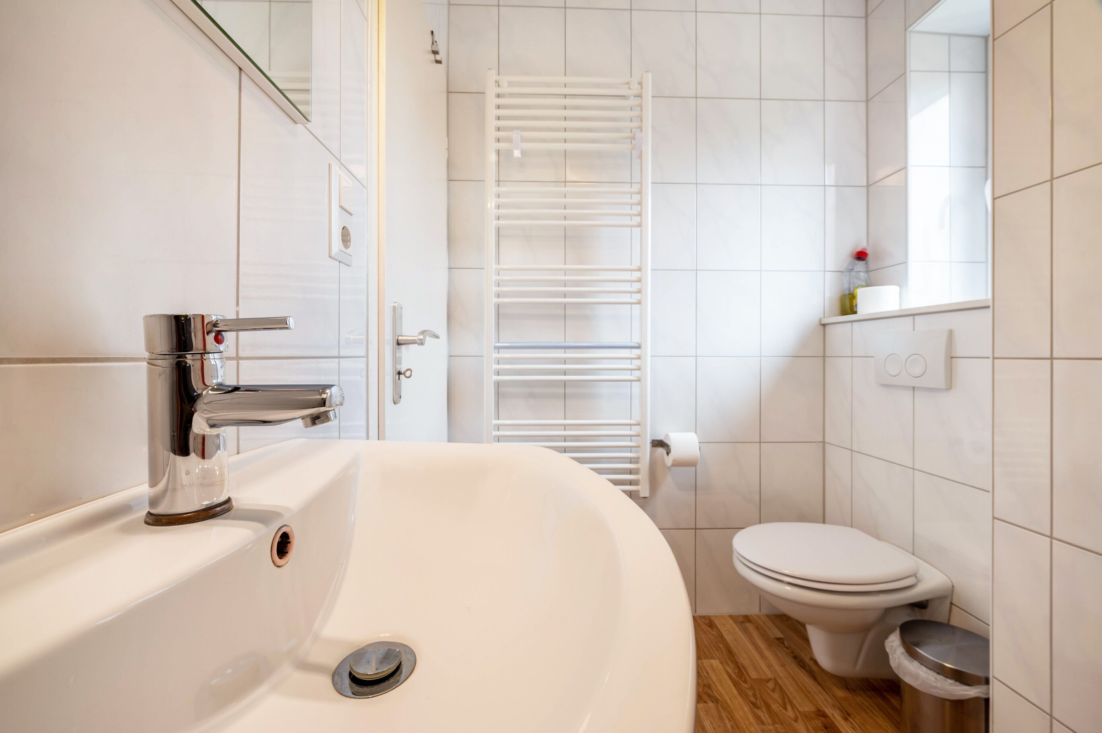 A bathroom with a white sink, a toilet, a towel rack, and a mirror.