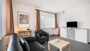 Una sala de estar moderna con un sofá, una silla, una mesa de centro, un televisor y un mueble.