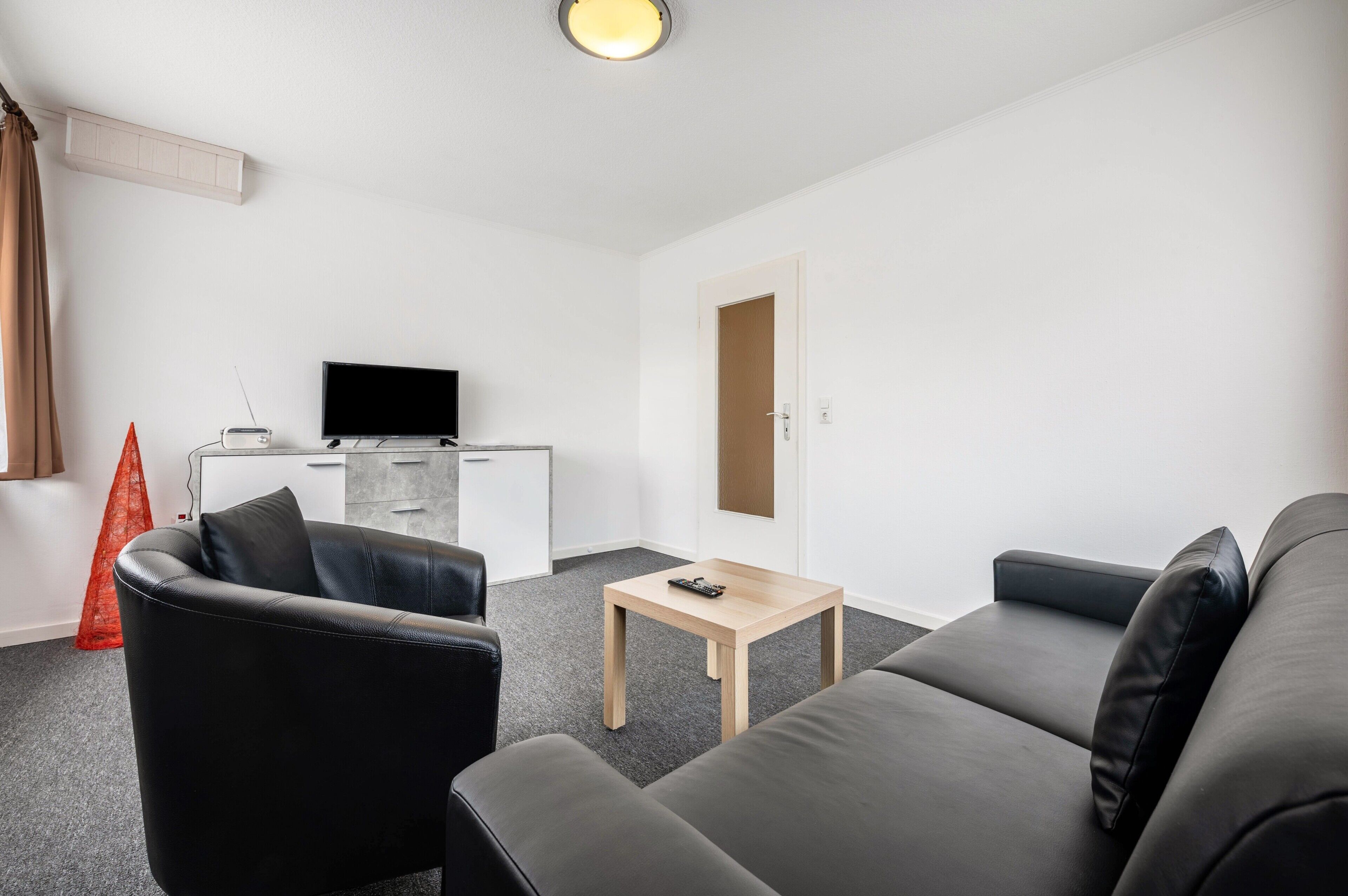 A modern living room with a sofa, a coffee table, a TV, and a small cabinet.
