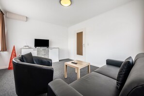 Un salon moderne comprenant un canapé, une table basse, un téléviseur et un petit meuble.