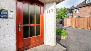 Una casa con puerta de madera, placa con número y pequeño jardín.