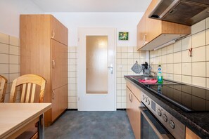Une cuisine de taille réduite, dotée de meubles de rangement en bois, d’une cuisinière et d’un dosseret carrelé.
