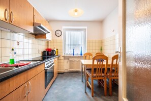 Une cuisine avec des meubles de rangement en bois, une cuisinière, un évier et une table à manger avec des chaises.