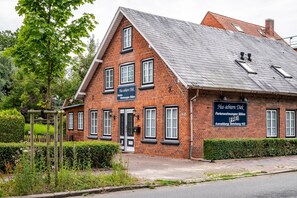 A red brick building with multiple windows and a sign indicating it is a guesthouse.