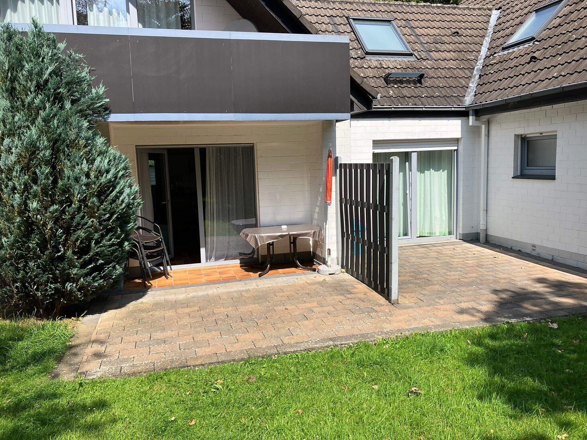 Une maison moderne dotée d’un patio, d’une porte-fenêtre coulissante, d’une petite table et d’une chaise.