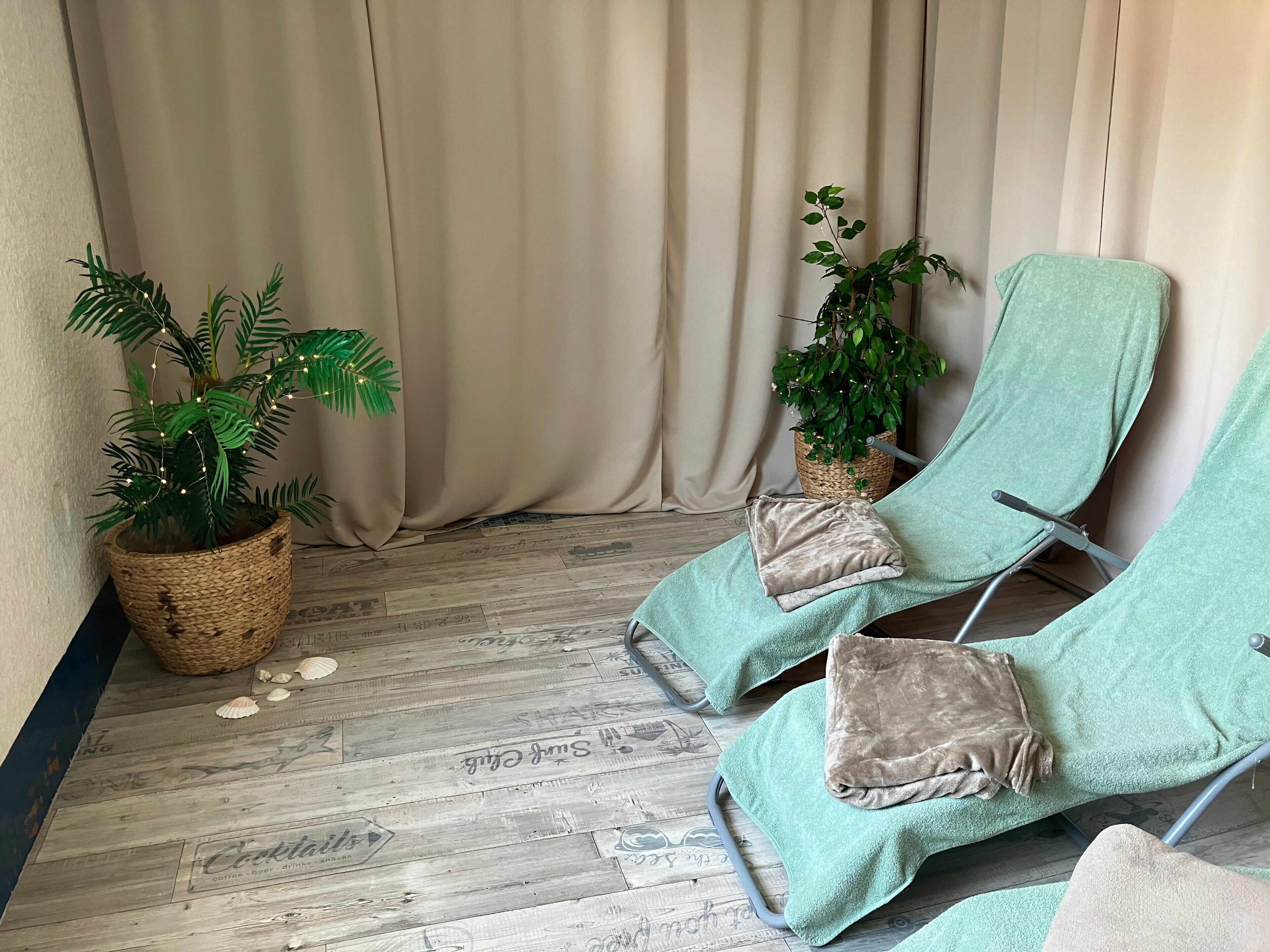 A spa area with two reclining chairs, a potted plant, and a wooden floor with nautical-themed tiles.