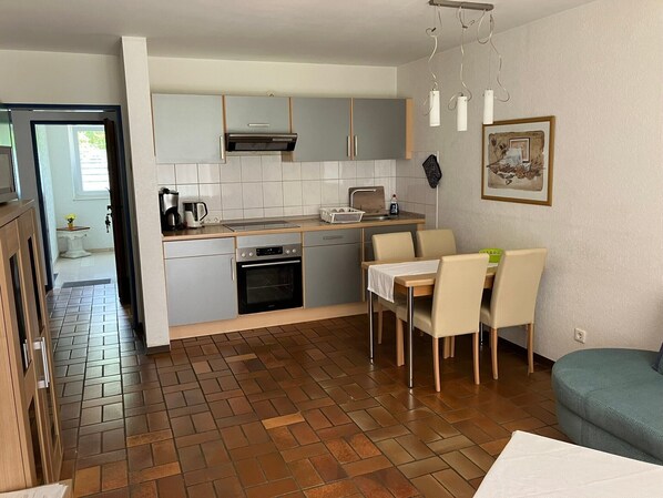 A compact kitchen with a dining area, a built-in oven, and a small refrigerator.