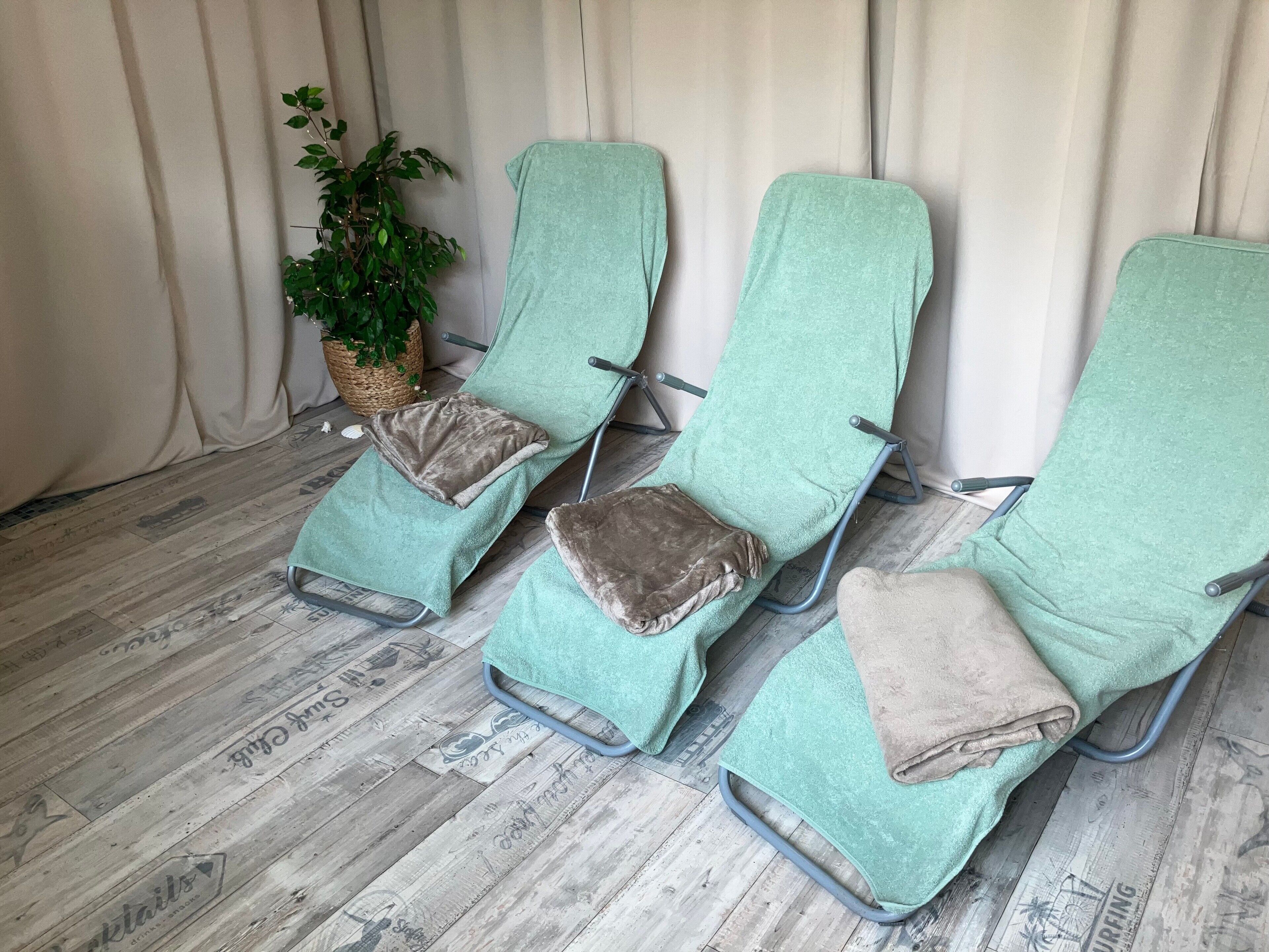 Three lounge chairs with green covers, arranged in a row against a curtain backdrop.