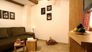 A cozy living room with a sofa, a small table with a book and a teapot, a basket, and a wooden counter with fruit. - Holiday Home 'Silberleiten' with Mountain View, Private Garden and Wi-Fi (Krimml)