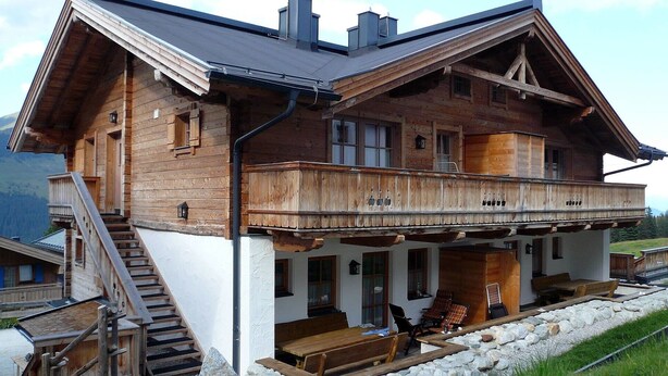 A wooden chalet with a balcony, a staircase, and outdoor seating. - Holiday Home 'Silberleiten' with Mountain View, Private Garden and Wi-Fi (Krimml)