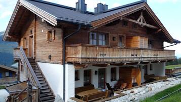 Eine Holzchalet mit Balkon, Treppe und Sitzgelegenheit im Freien.