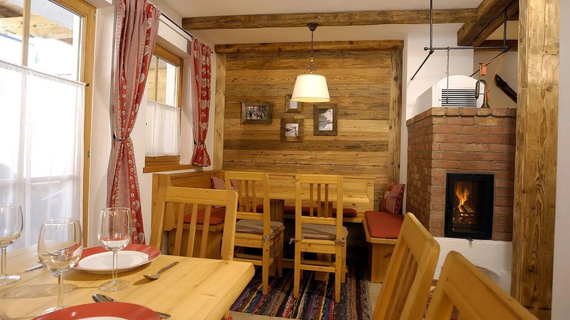 Ein rustikaler Essbereich mit Holzkubaturen, einem Kamin und einem Fenster mit Vorhängen.