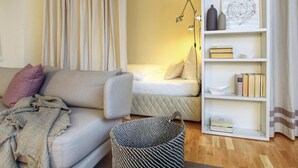 Ein gemütliches Zimmer mit einer Couch, einem Bett, einem Bücherregal und einer Lampe.
