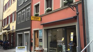 Straßenansicht eines Gebäudes mit einer Ladenfront, auf der das Schild 'Des Barfüßchen' steht.