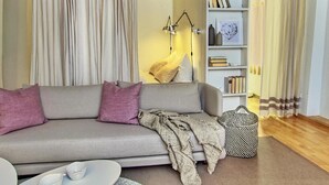 Ein modernes Wohnzimmer mit einem grauen Sofa, einem Couchtisch, einer Bücherwand und einer gemusterten Tasche.