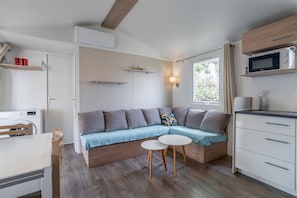 Un espace de vie compact comprenant un canapé, une petite table à manger, un four à micro-ondes et un meuble en bois.