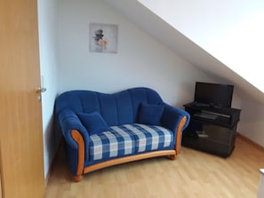 A room with a blue sofa, a small wooden cabinet, and a framed picture on the wall. - Apartment 'Buffler' with Mountain View and Wi-Fi (Lindau)