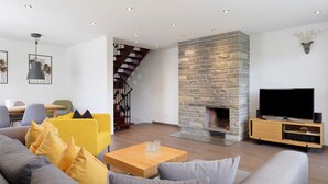 Een moderne woonkamer met een stenen openhaard, een flatscreen televisie en een trap.