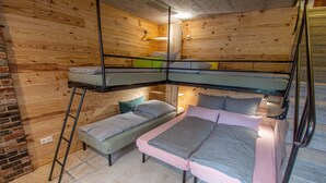 Dormitorio con literas, una mesita y pared de ladrillo.
