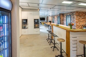 Una cocina moderna con armarios blancos, electrodomésticos de acero inoxidable y una barra alargada con taburetes.