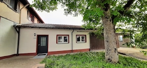 Un bâtiment doté d’un toit recouvert de tuiles, d’une porte et de deux fenêtres.