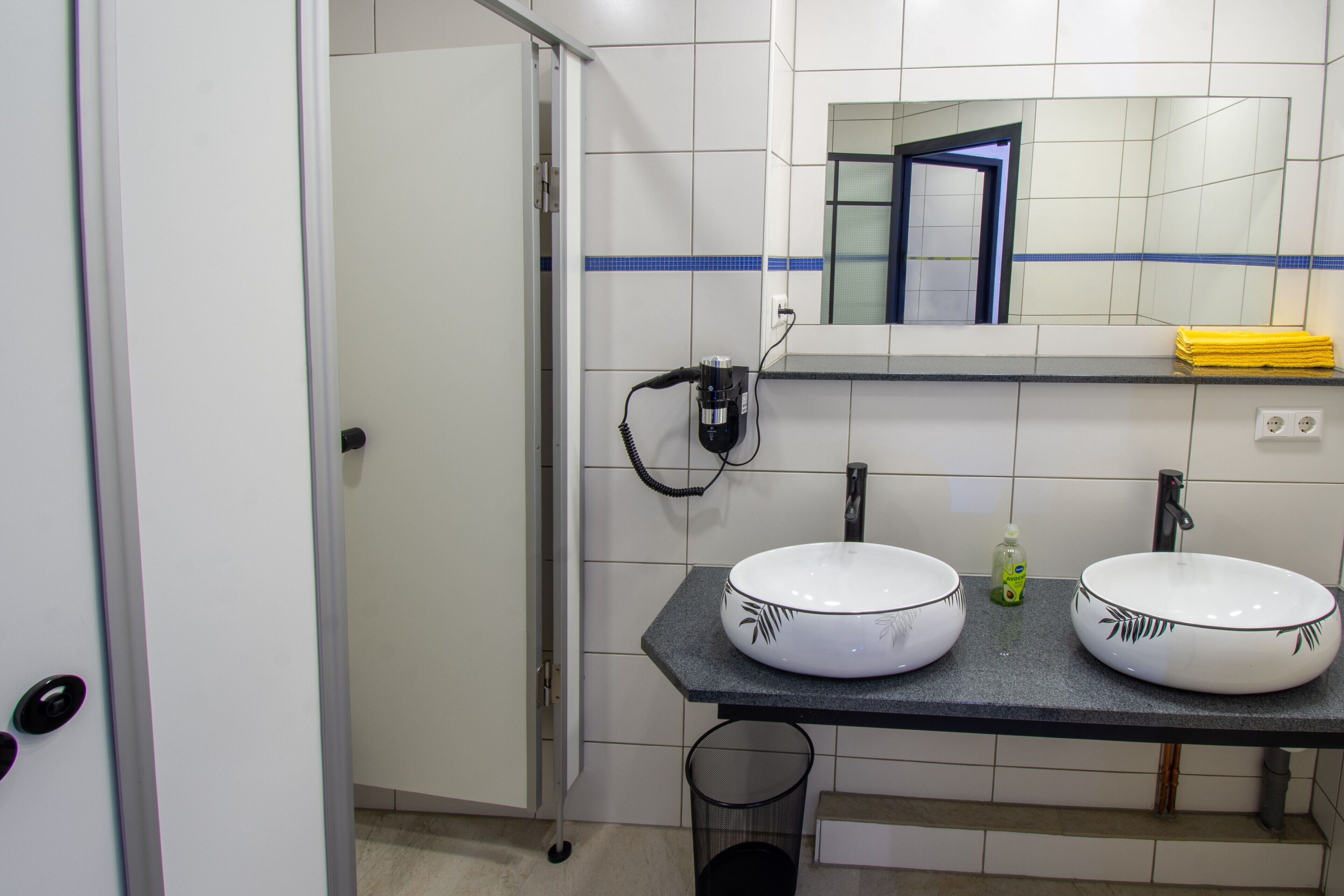 Een badkamer met twee wastafels, een spiegel en een handdoekhouder.