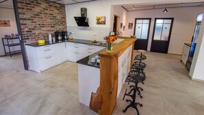 Una cocina moderna con una isla central, muebles blancos, una pared decorativa de ladrillo y una zona de bar con taburetes de madera.