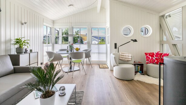 Un salon moderne comprenant un canapé, une table à manger, des chaises et un téléviseur.