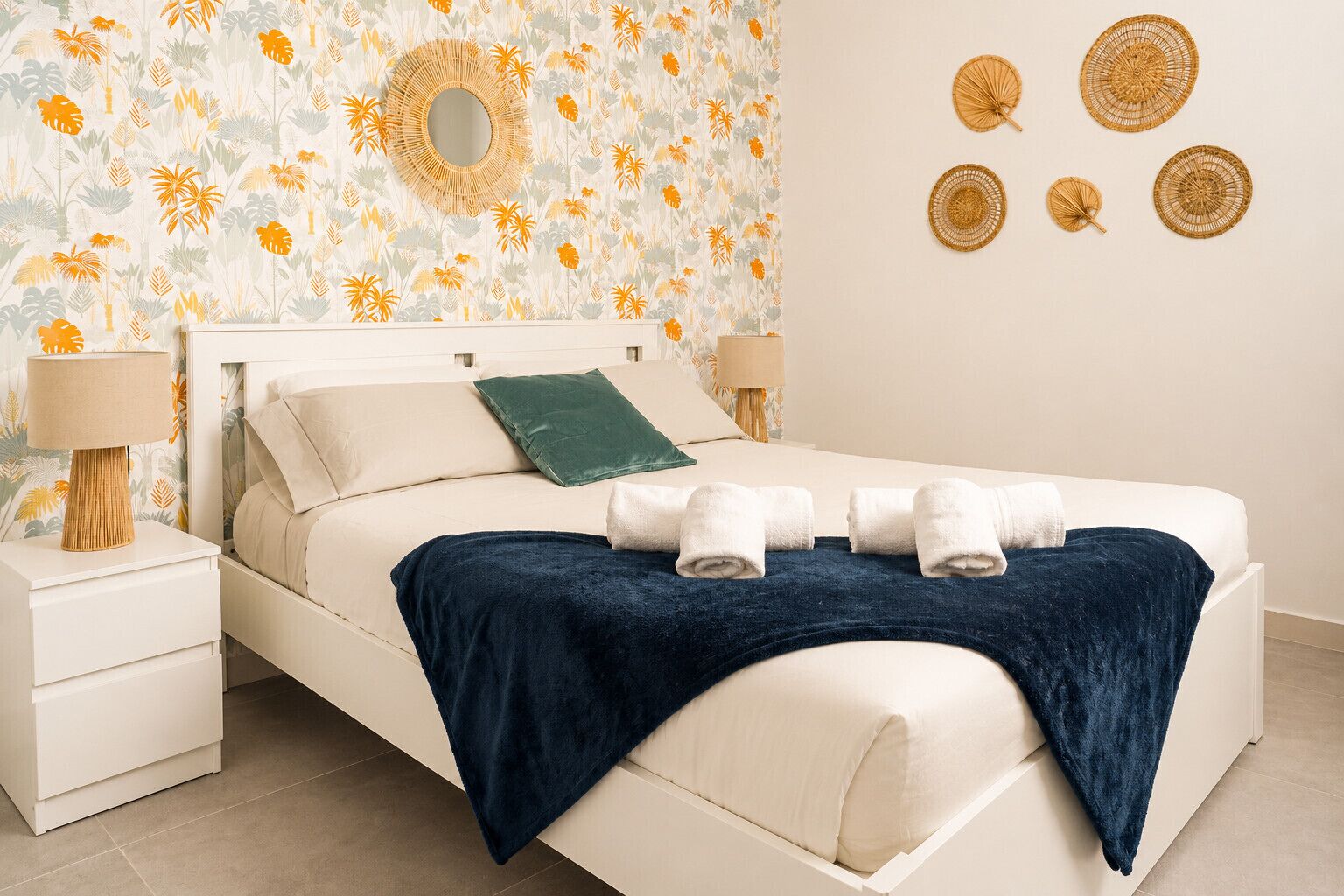 Een slaapkamer met een bed, nachtkastjes, een spiegel en wanddecoraties.