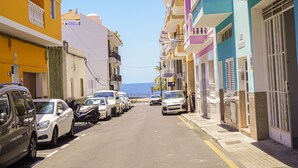 A narrow street lined with colorful buildings, parked cars, and a clear view of the sea. - Costa Relax - Modern apartment near the beach in Playa San Juan (Playa de San Juan)