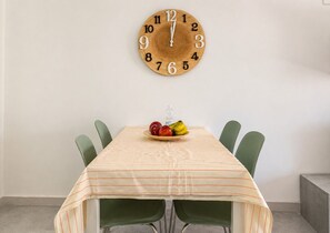 Una mesa de comedor con un reloj, sillas y un frutero.