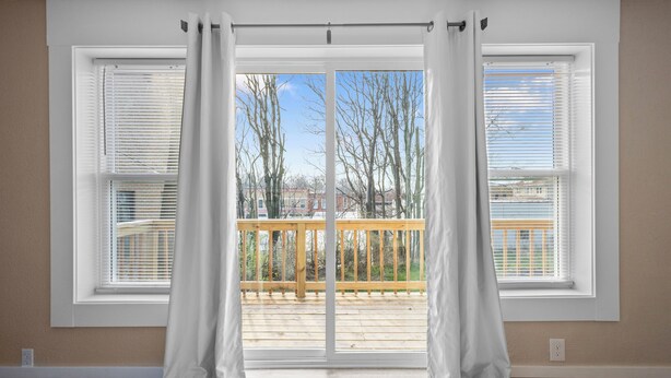 Una habitación con un amplio ventanal corredero que da a una terraza de madera.