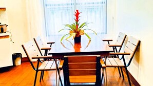 Un coin repas avec une table et des chaises en bois, une plante en pot et une fenêtre avec des rideaux.