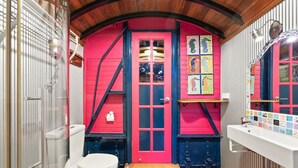 A bathroom with a red door, a white toilet, and a sink with a tiled backsplash. - Stylish Studio on South terrace. 2 Minute walk to the beach. (South Fremantle)