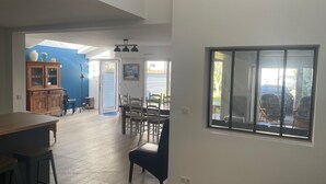 Un vaste espace de vie comprenant une table à manger et des chaises, un meuble en bois et une grande fenêtre donnant sur l’extérieur.