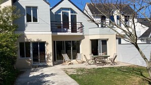 Une maison à deux étages avec un porche à l’avant, un petit patio et une pelouse.