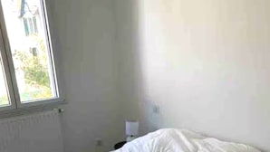 Une chambre avec un lit simple, une fenêtre et une table de chevet.