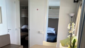 Een knus ingerichte kamer met een bed, een slaapbank, een eettafel met stoelen en een kleine keukenhoek.