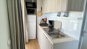 Een kleine keuken met een magnetron, fornuis en spoelbak.