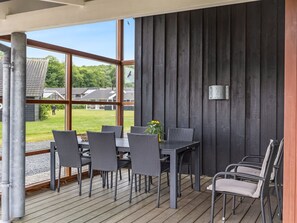 Een terras buiten met een tafel en stoelen, een uitzicht op huizen en een houten muur.