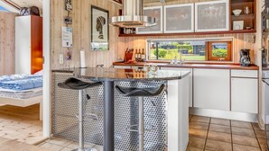 Una cocina moderna con una isla central, armarios de madera y un amplio ventanal con vistas al exterior.