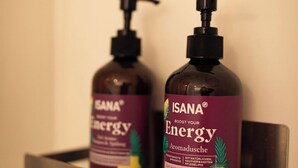 Dos botellas de ISANA Energy aromadusche sobre una estantería metálica en un baño.