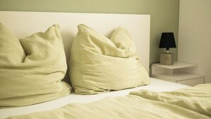 Una cama con dos almohadas y una mesita de noche con lámpara.