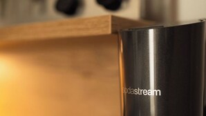 Una cocina con electrodomésticos negros, un estante de madera en la parte superior y un fondo desenfocado.
