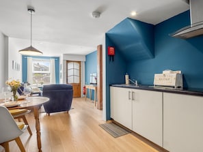 Eine moderne Küche mit weißen Schränken, einer blauen Akzentwand und einer Brokiste auf der Arbeitsfläche.