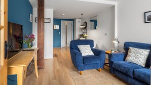 A modern living room with a blue sofa, a wooden table, and a blue armchair.